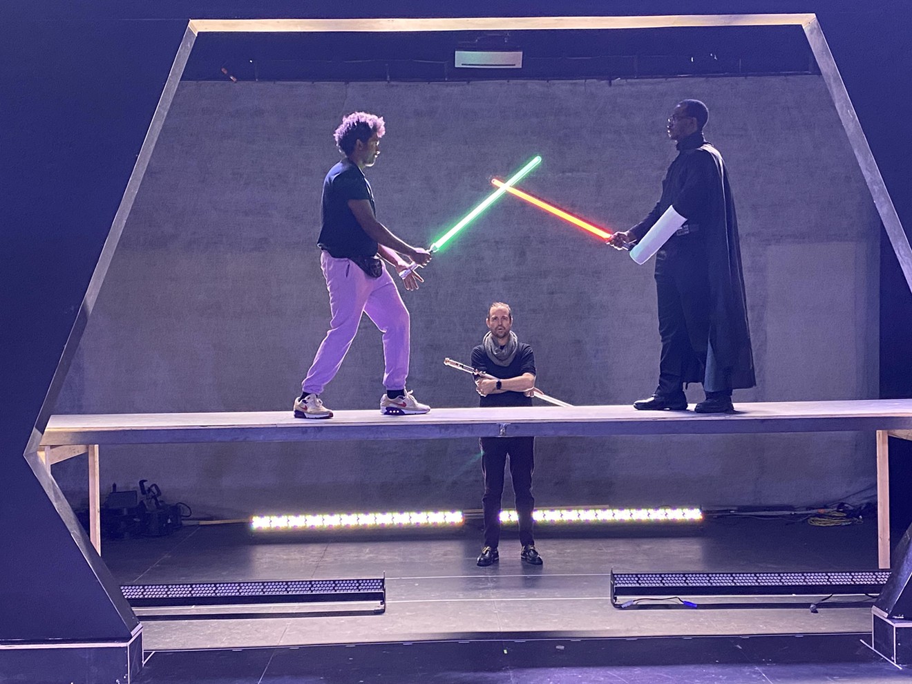 Director Geoffrey Kent oversees a lightsaber fight between Mykail Cooley (left) and Rashad Holland (right).