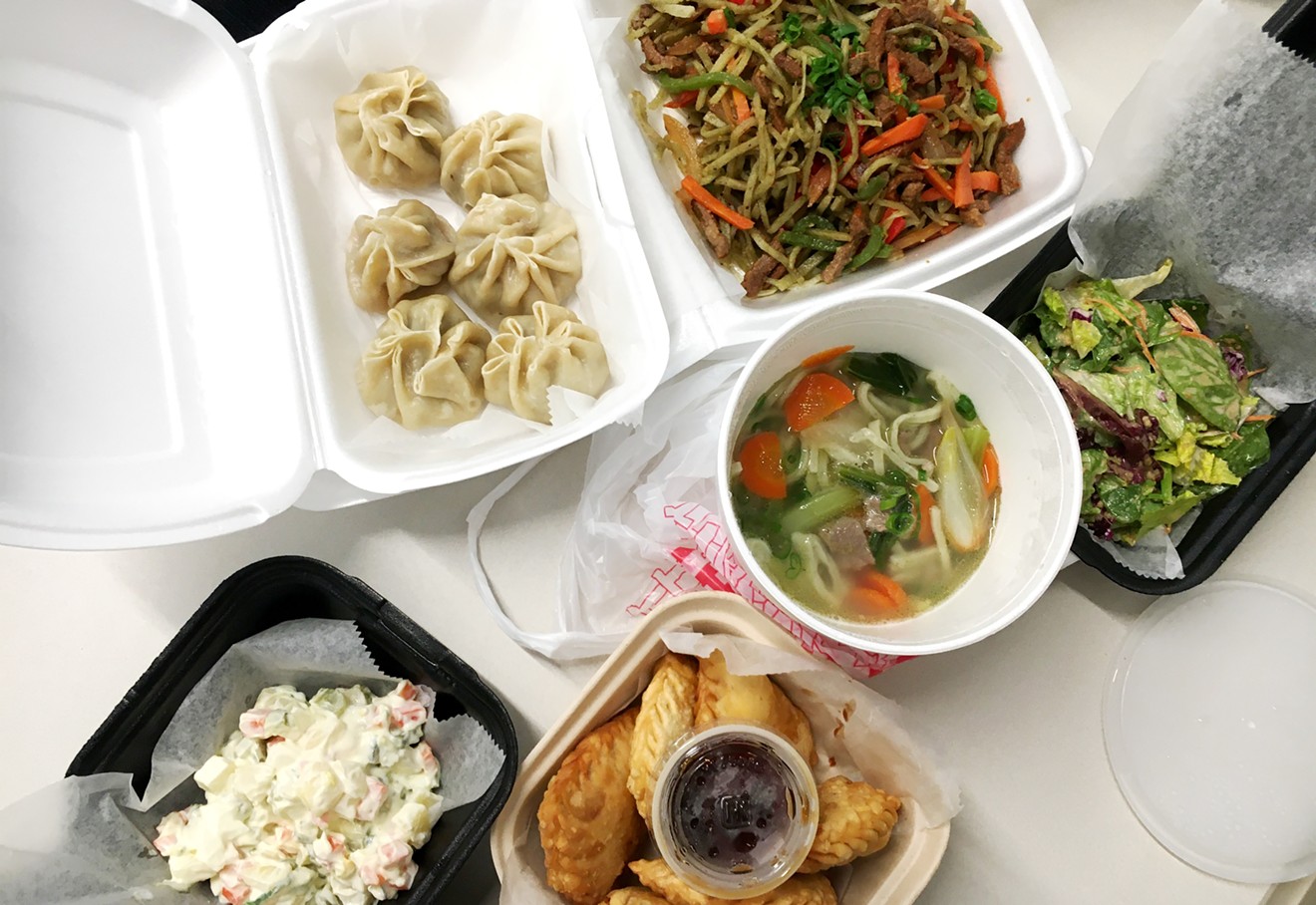 A takeout bonanza from Sushi Kai & Mongolian Cuisine. Clockwise from top right: Tsuivan, side salad, lamb noodle soup,  kuushuur, potato salad and buuz.
