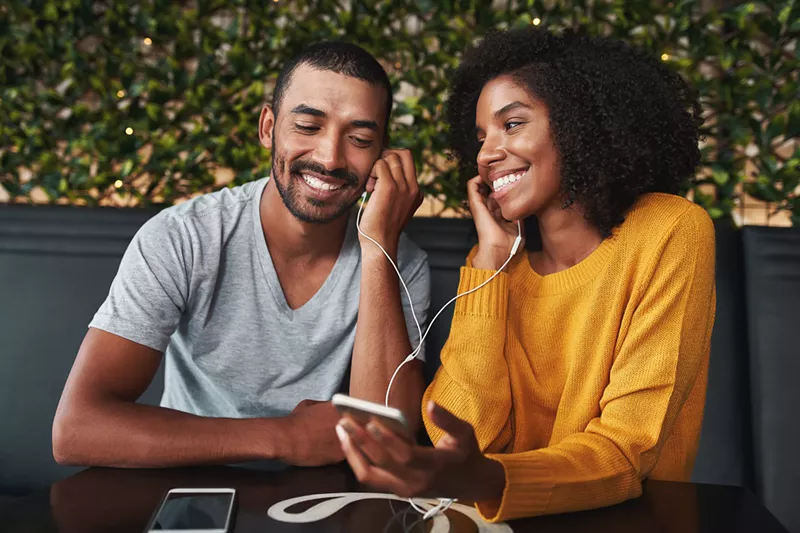 Image: two people listening to music through the same set of headphones