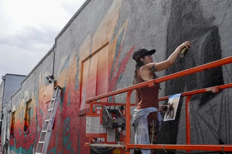 Image: Cromaj begins to fill in her outline for a collaborative wall behind Erico Motorsports.