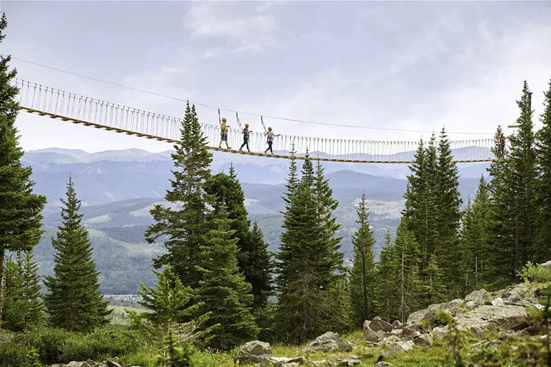 Image: Three people backdropped by mountains while crossing the aerial bridge at Breckenridge Ski Resort