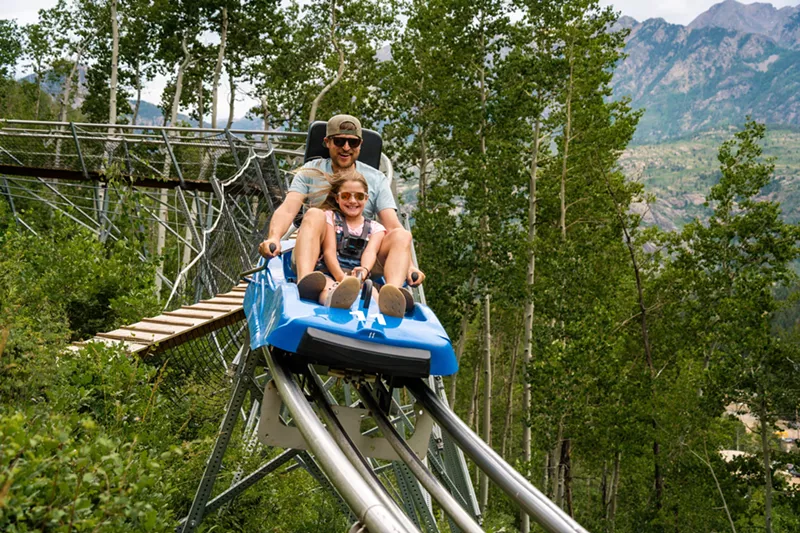 Image: A man and young girl riding the mountain coaster at Purgatory Resort