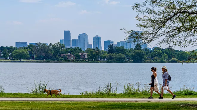 People walk a dog near a lake