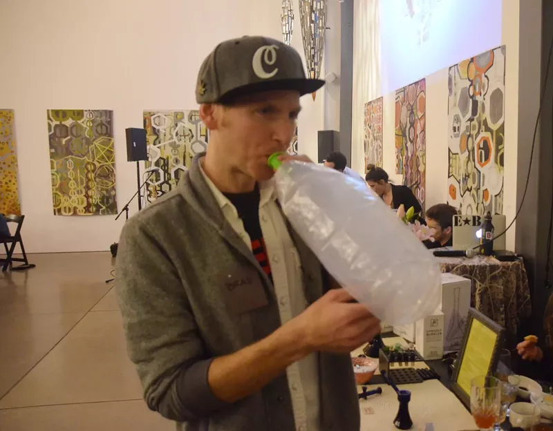 Image: A man hits a vaporizer bag at Mason Jar's 4/20 dinner at Space Gallery.