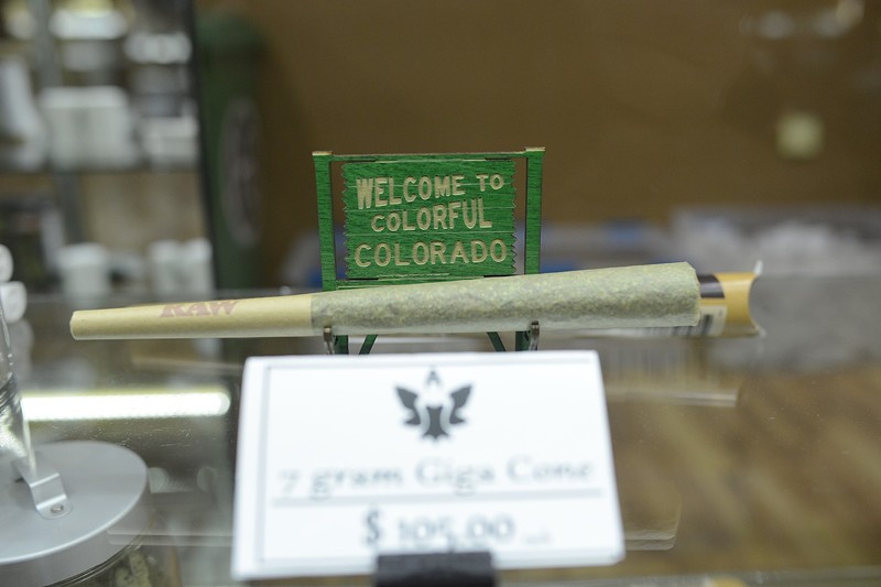 A marijuana joint in front of a Colorful Colorado sign
