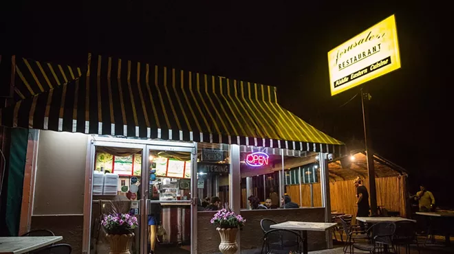 the outside of a restaurant with a yellow, lit up sign