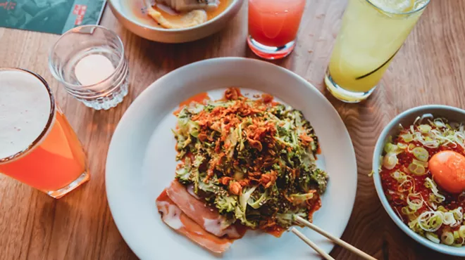 vegetables on top of thin-shaved ham on a plate surrounded by various drinks