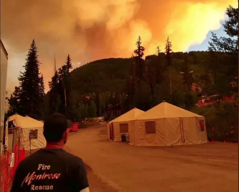 Image: A member of the "Wildland" crew looks toward the largely uncontained blaze.