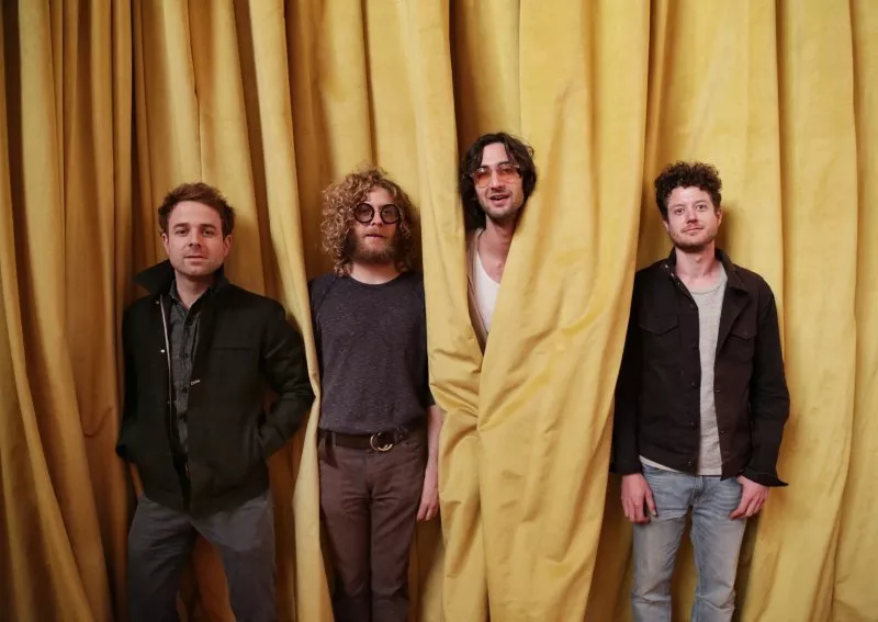 Image: Four musicians in front of yellow curtain