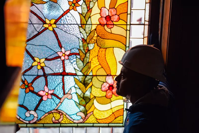 Image: Moises Torres stands in front of restored windows at the Molly Brown House Museum.