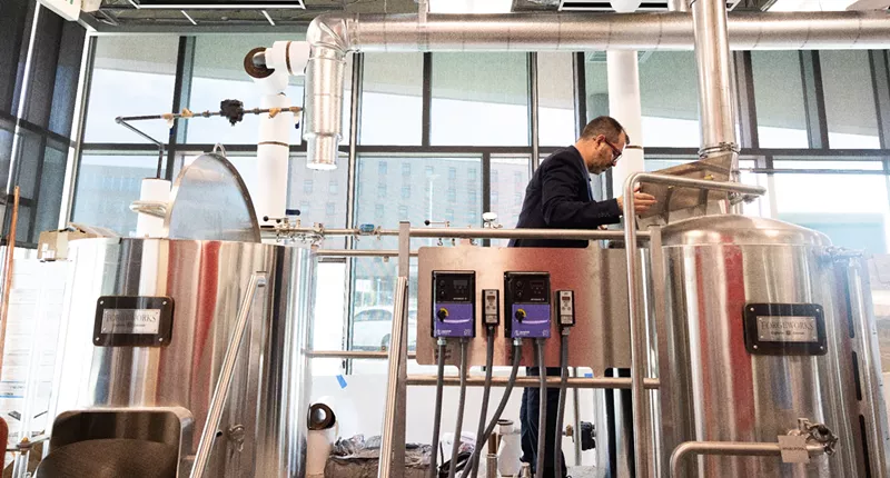 Image: a man standing new brewing equipment