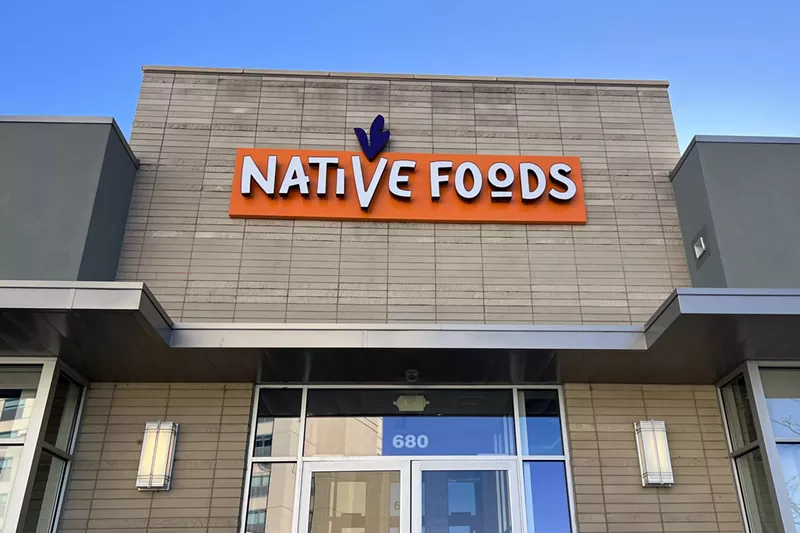 Image: A tan brick building with orange signage reading "Native Foods"