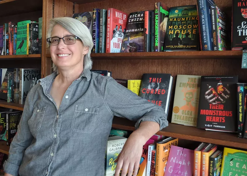 Image: A woman next to bookshelves