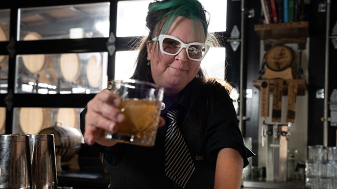 a woman with teal hair and a black and white striped ties holding a cocktail