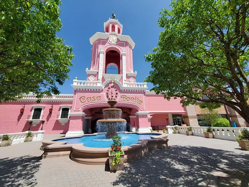 Image: a fountain in front of a large pink building