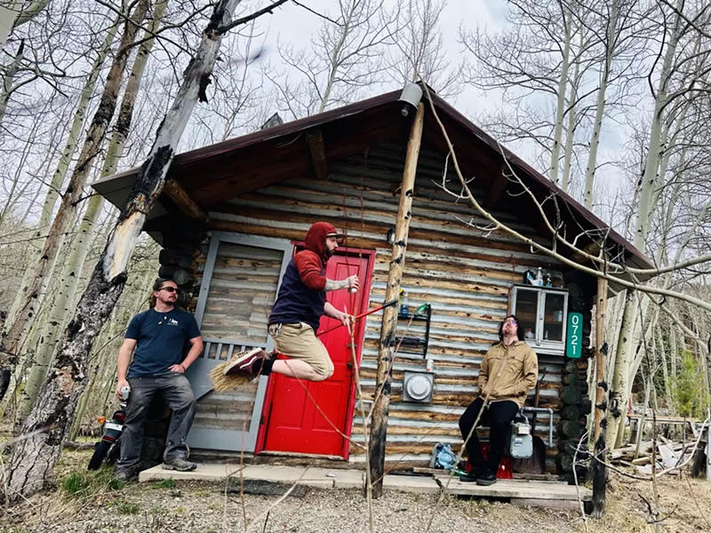 Image: three men in front of cabin