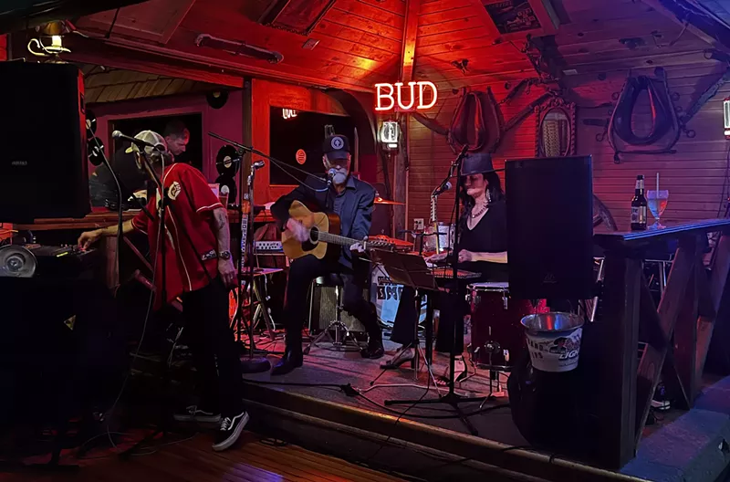 Image: band performing on stage with red and purple lighting
