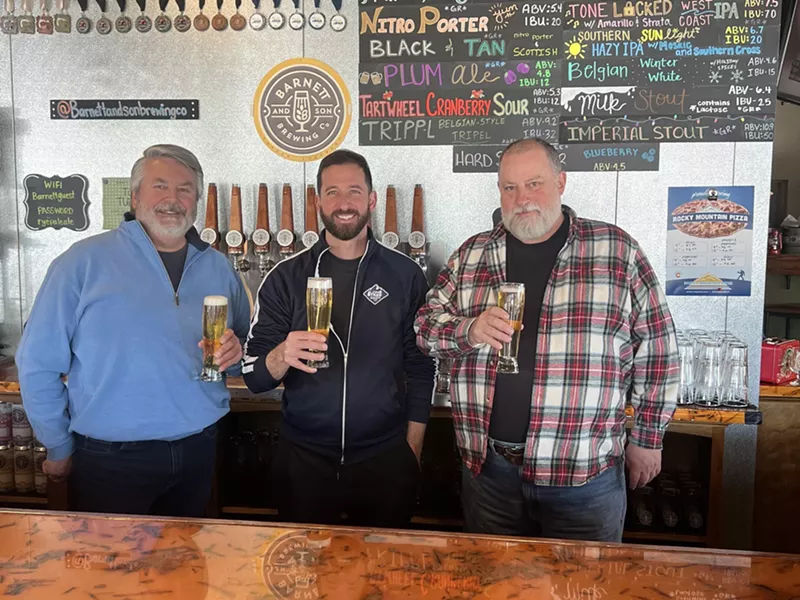 Image: Three men standing behind a bar.