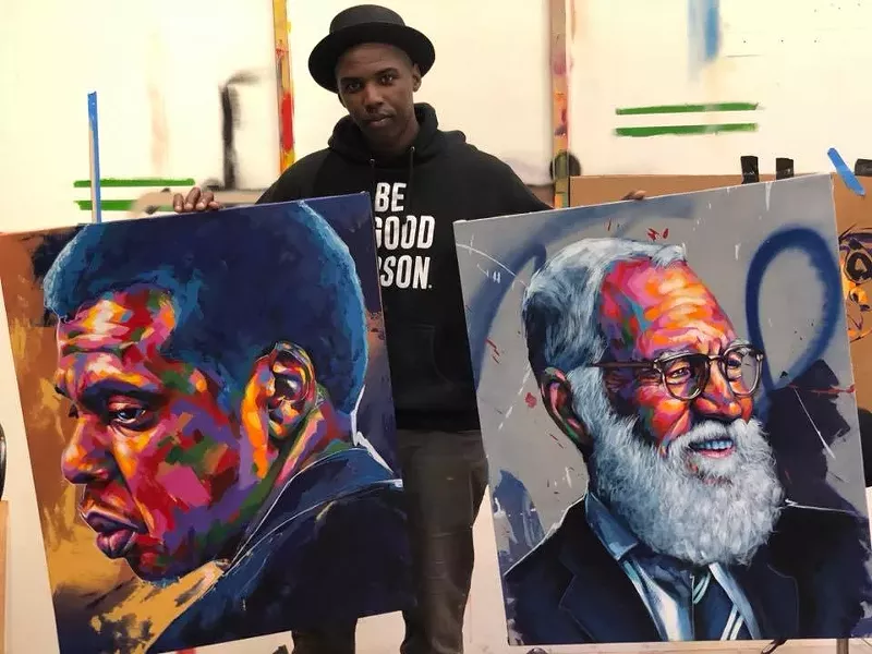 Image: Thomas "Detour" Evans poses with his portraits.