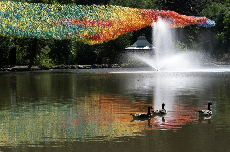 Image: Colorful streamers hang over a body of water with ducks swimming