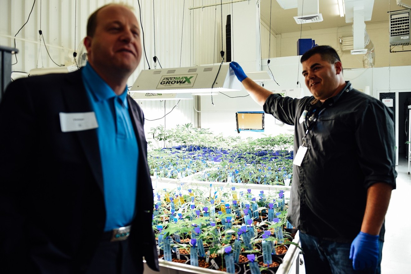 Lama Brand Cannabis co-founder Tony Karas shows Colorado Governor Jared Polis around his cultivation during a dispensary tour in 2018.