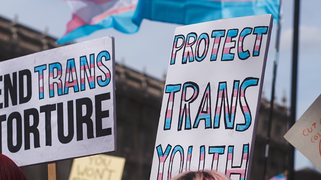 A protestor holds a sign that says "protect trans youth."