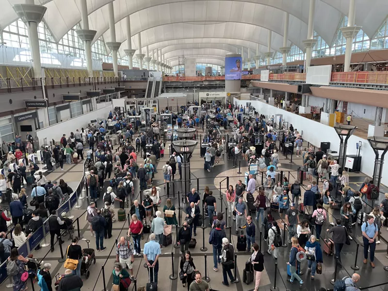 Image: People wind their way through a security line in a hall with a domed roof.