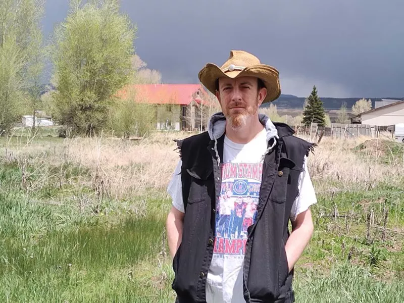 Image: man in vest and hat standing outside