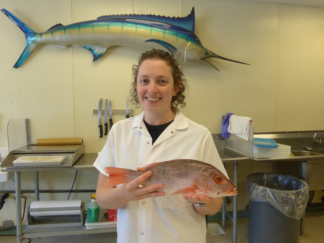 Tala Carr displays a fresh red snapper at Tom's Seafood.