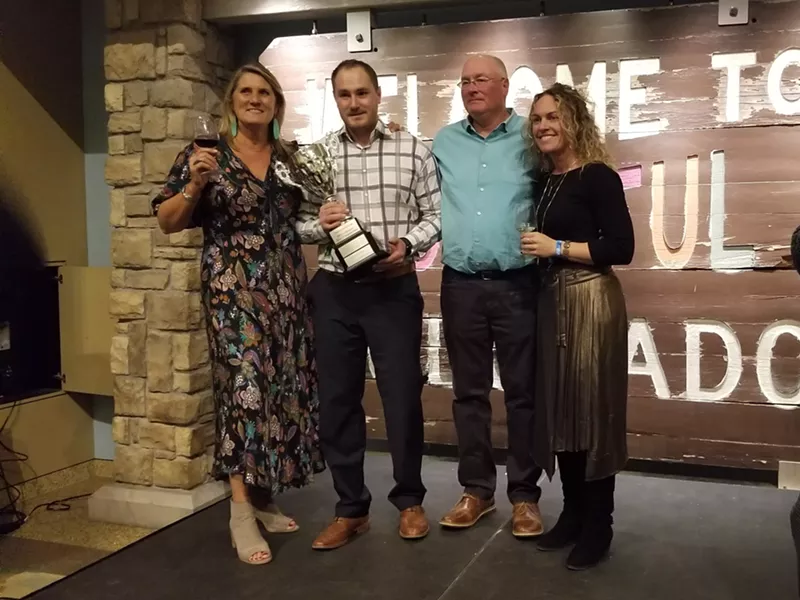 Image: Kate Greenberg, Commissioner of the Colorado Department of Agriculture, congratulates Qutori Wines owner Julie Bennett, vintner Tyler Bennett, and husband Richard Bennett.