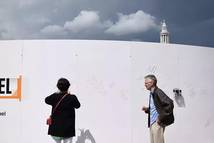 Dr. Varsha Lafargue, left, and Jeffery Kooistra sign the back side of the opioid memorial wall. Kooistra's twin sister died of an opioid overdose. - KENZIE BRUCE