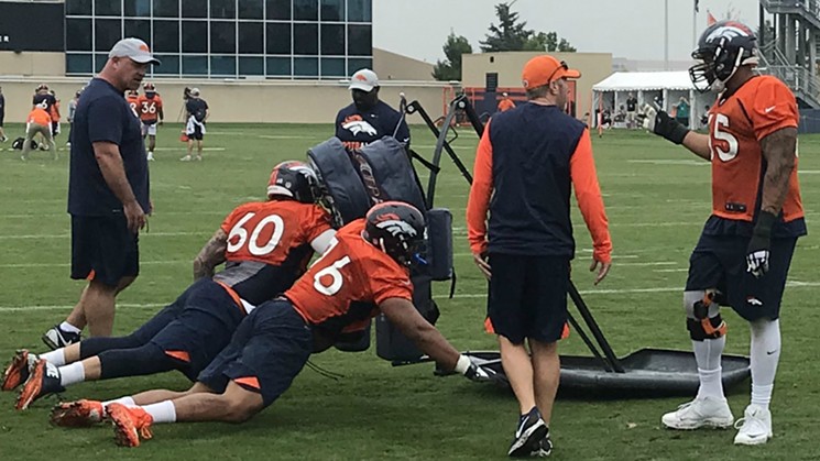 Offensive lineman Connor McGovern and Max Garcia execute the from-the-knees blocking sled drill as guard Ron Leary looks on. - PHOTO BY LORA ROBERTS