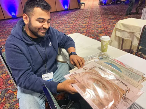 Sahil Shetye admiring some of the flat-Earth maps that he bought for his colleagues in Chicago. Shetye believes the Earth is spherical. - CONOR MCCORMICK-CAVANAGH