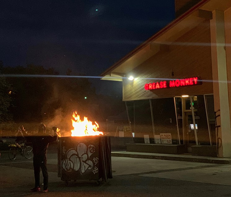 A protester holds his fists up in front of a burning dumpster on the night of May 31 on the corner of Corona and Colfax. - LEE ANN DENARD