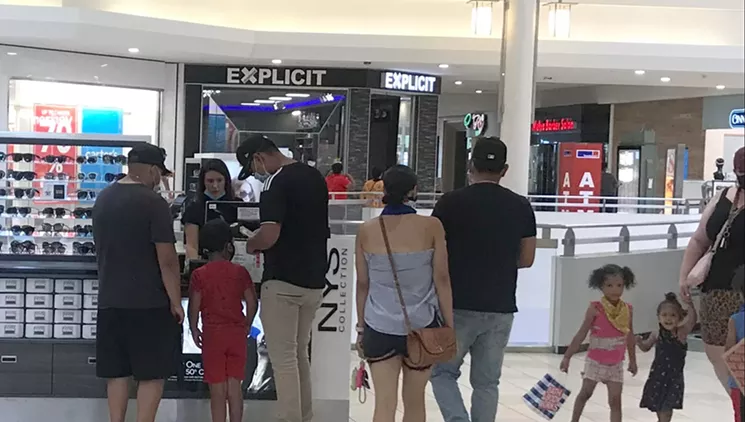 This employee at Aurora Mall was one of several showing off her nose while working at a kiosk. - PHOTO BY MICHAEL ROBERTS