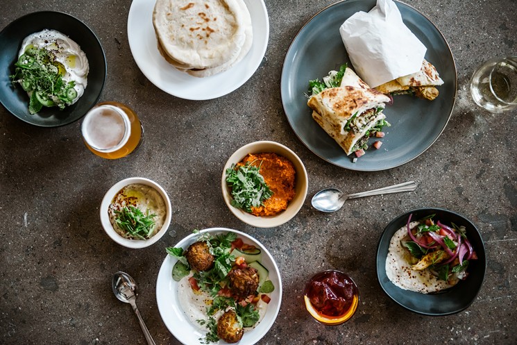 An assortment of Israeli shareables from Boychik, including falafel, hummus, muhammara, labneh and chicken shawarmas. - LUCY BEAUGARD