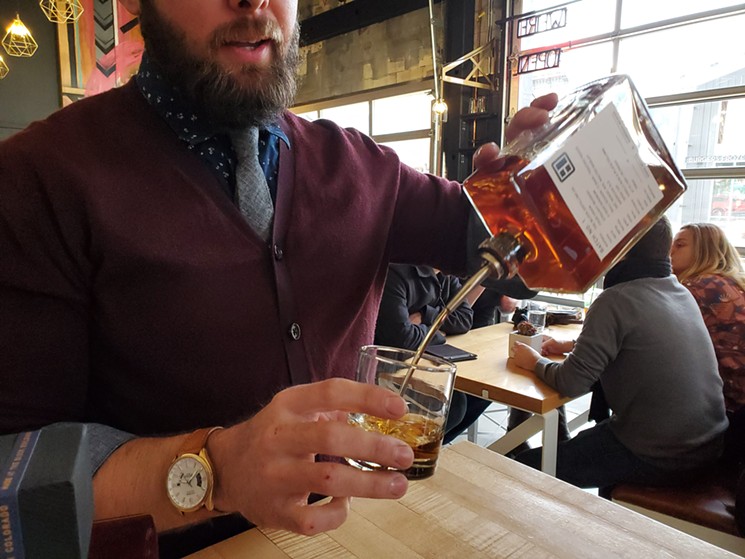 The Block's Kraig Weaver pours a taste of his first batch of whiskey. - LINNEA COVINGTON