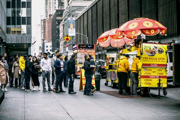 Customers line up at the original Halal Guys cart in New York City. - COURTESY OF THE HALAL GUYS