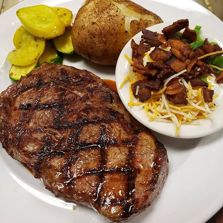 a steak on a plate with a loaded baked potato