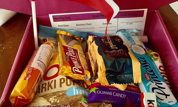 Each box contains twelve sweet and salty treats, along with country facts and flag souvenirs. - COURTESY OF OME ENEBELI