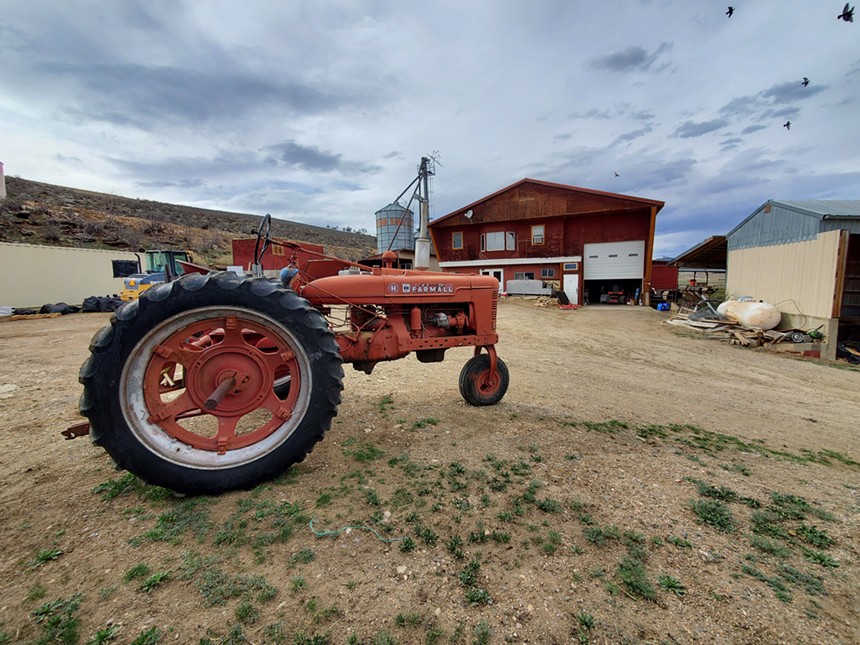 a red tractor in front of a large red barn