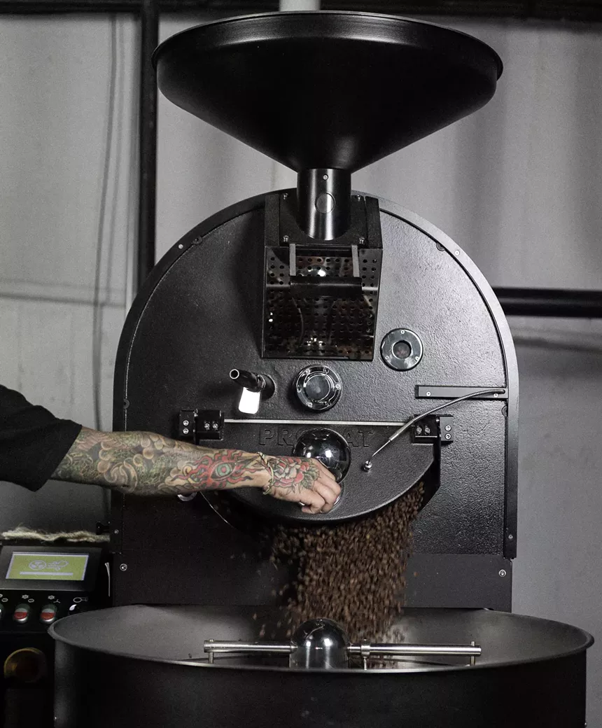 a coffee roaster in use with beans pouring out