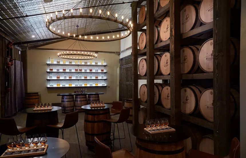 a room in a distillery with tables and barrels