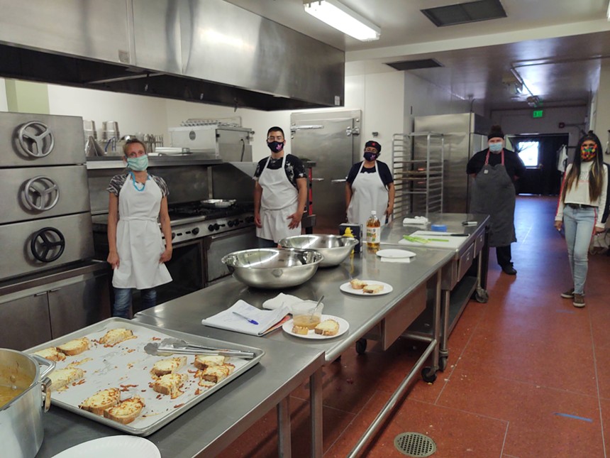 people in aprons standing in a commercial kitchen