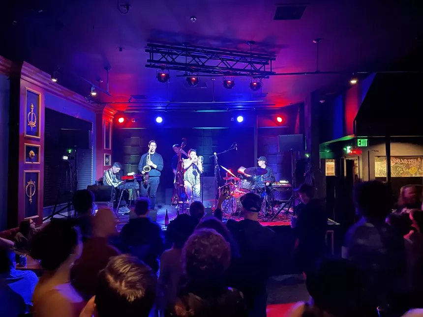a horn band plays on stage with blue and red lighting