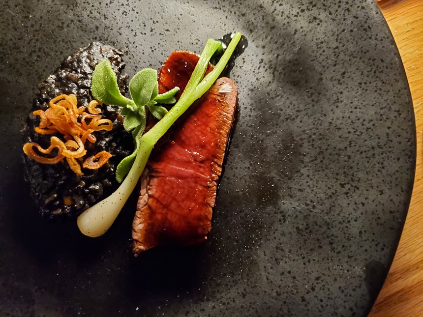 a piece of buffalo steak with ramps and black rice