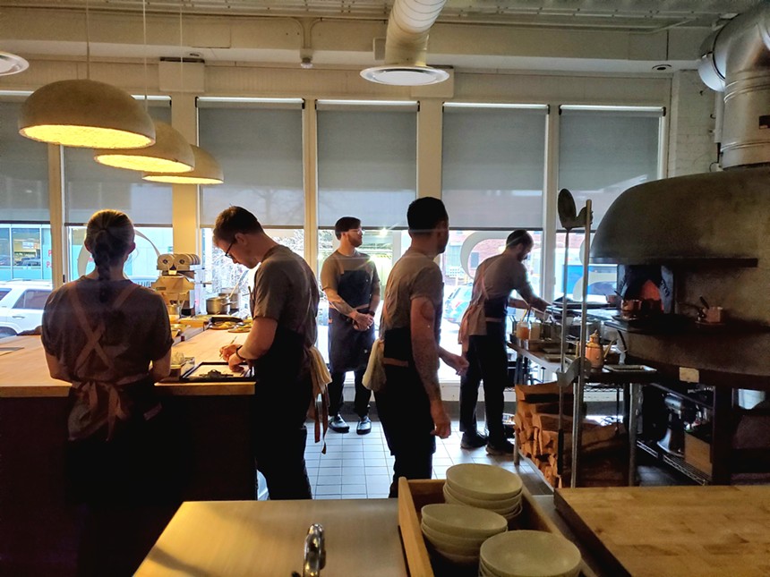 five chefs in aprons working in an open kitchen