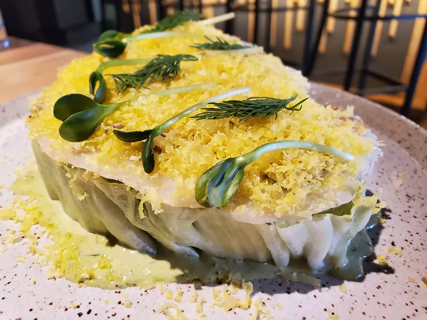 a flat wedge of iceberg lettuce topped with grated cured egg yolk