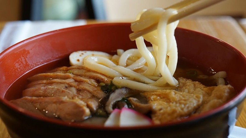 Chopsticks holding noodles over a bowl