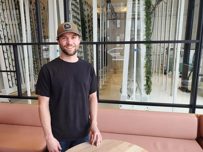 a man in a black t-shirt standing in front of a glass wall